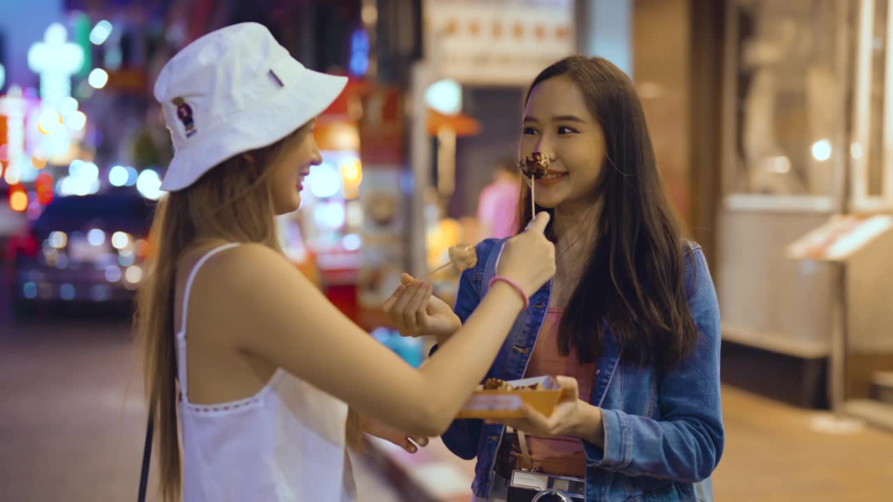 两个年轻女人在夜市吃东西视频素材