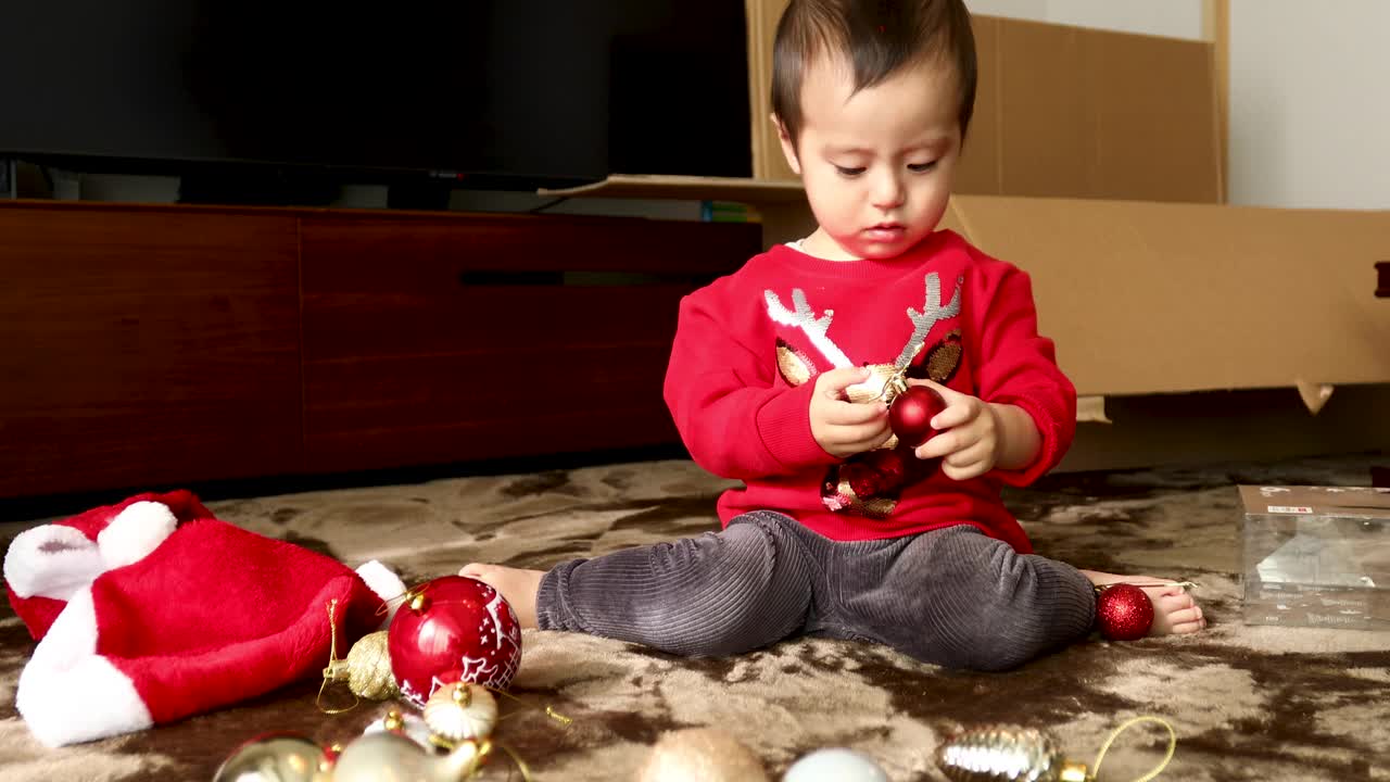 一个小男孩好奇地盯着圣诞树上的装饰品视频下载