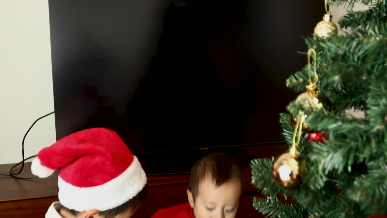 一个哥哥抱起他的弟弟，帮他装饰圣诞树视频下载
