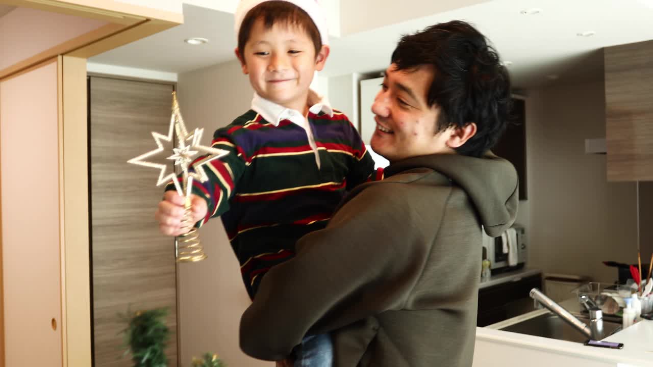 一个男孩用星星装饰圣诞树的顶部视频下载