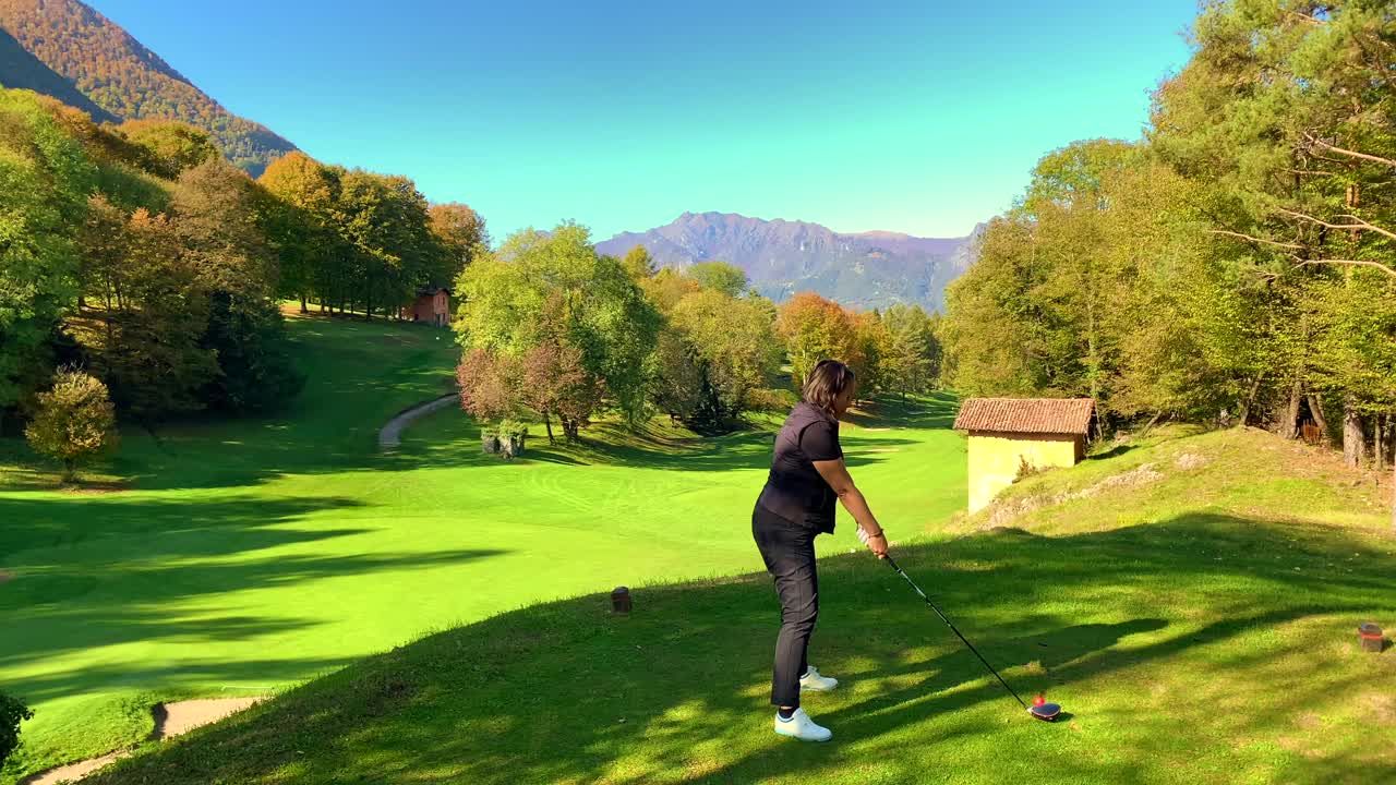 高尔夫球手与她的高尔夫俱乐部司机在一个阳光明媚的日子与山景城视频素材
