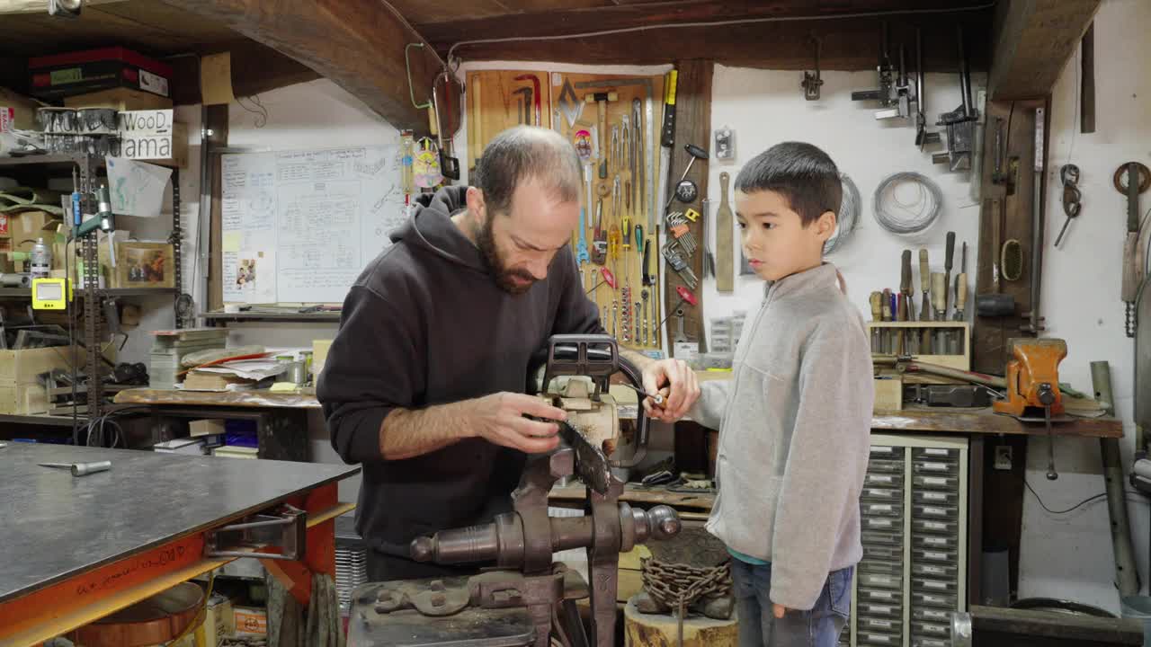 (中景)一位父亲教他的儿子如何磨链锯视频下载