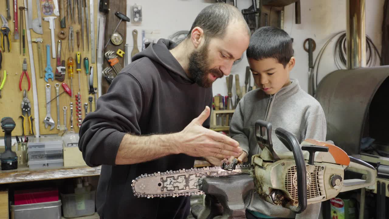 (中景)一位父亲教他的儿子如何磨链锯视频下载