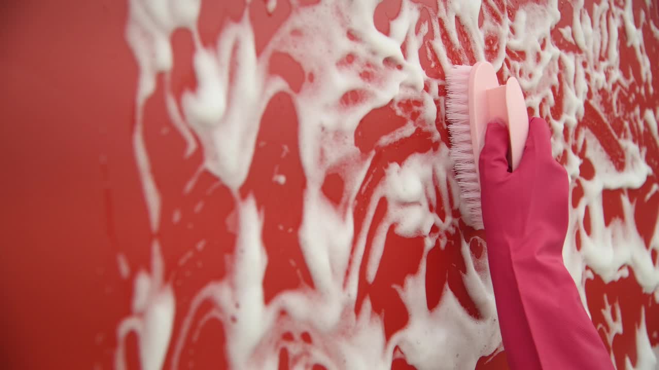 妇女用刷子手清洗红色的墙视频素材