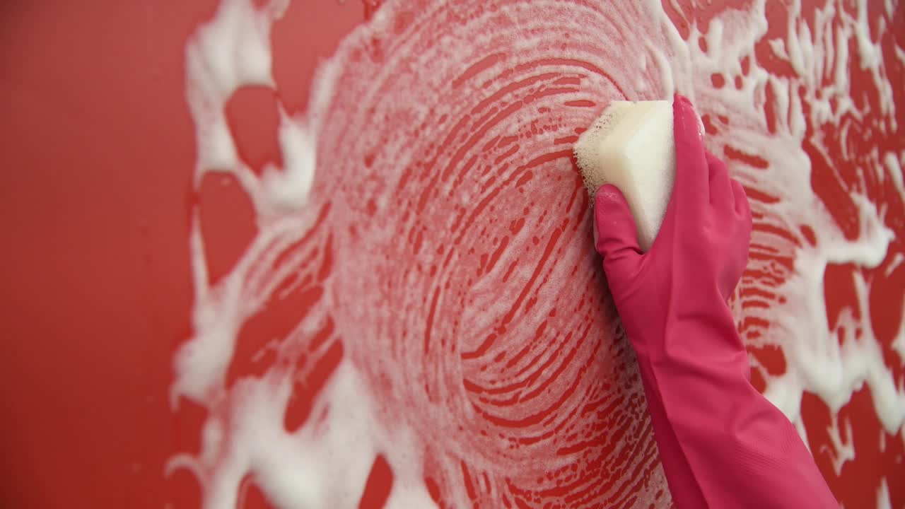 妇女用海绵手洗红墙视频素材