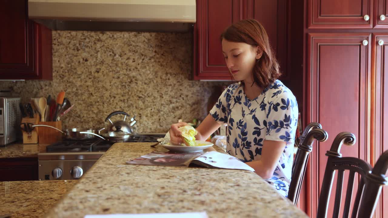 一名少女一边吃着烤面包上的鸡蛋一边看杂志视频下载