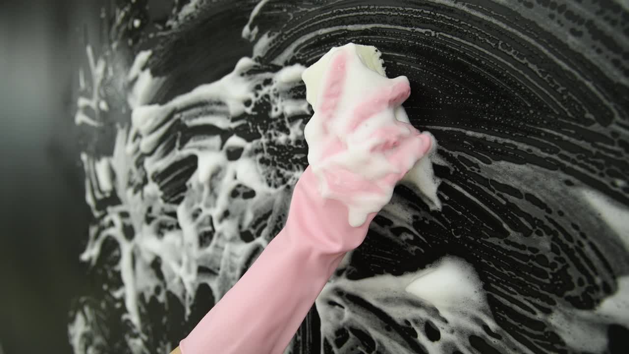 妇女用海绵手清洗黑色墙壁视频素材