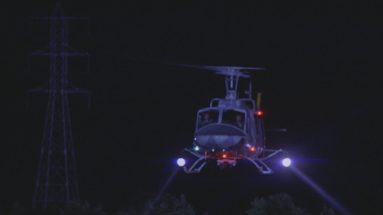 跟踪拍摄的直升机与探照灯和乘客飞越森林或树木。可能是森林大火。视频素材