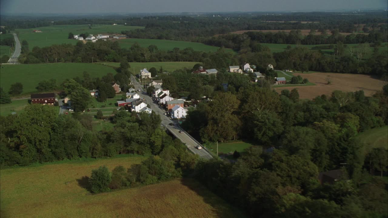 农村地区或乡村小镇的空中拍摄。两车道道路两旁各有多层房屋。视频下载