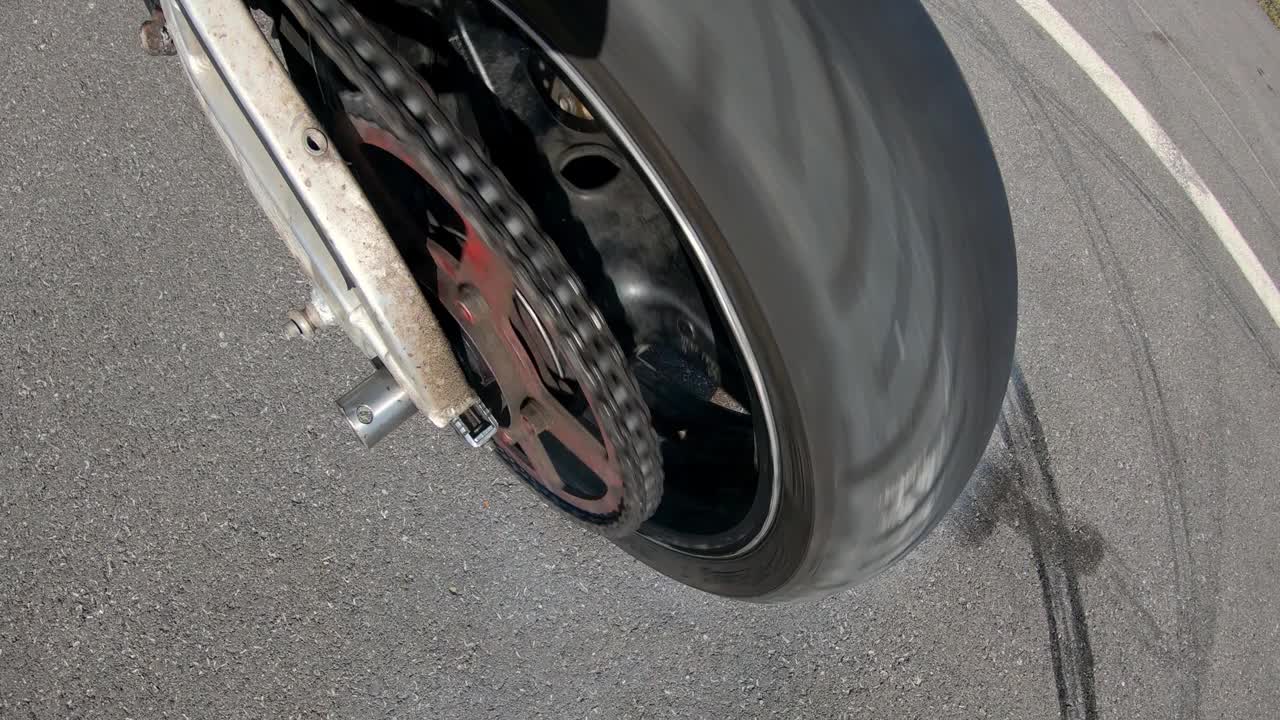 轮胎烧毁，烟从车轮下出来，由于轮胎摩擦沥青。摩托车手做特技，在摩托车上漂移。慢动作视频素材