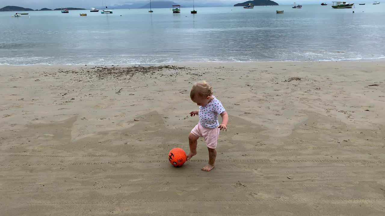刚学会走路的女孩和弟弟在海滩度假时玩球视频下载