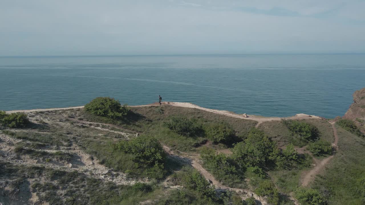 无人机观察主动徒步旅行的人与背包沿着小径岩石山附近的蓝色海岸与天空地平线在户外休闲娱乐活动旅行与复制空间视频下载