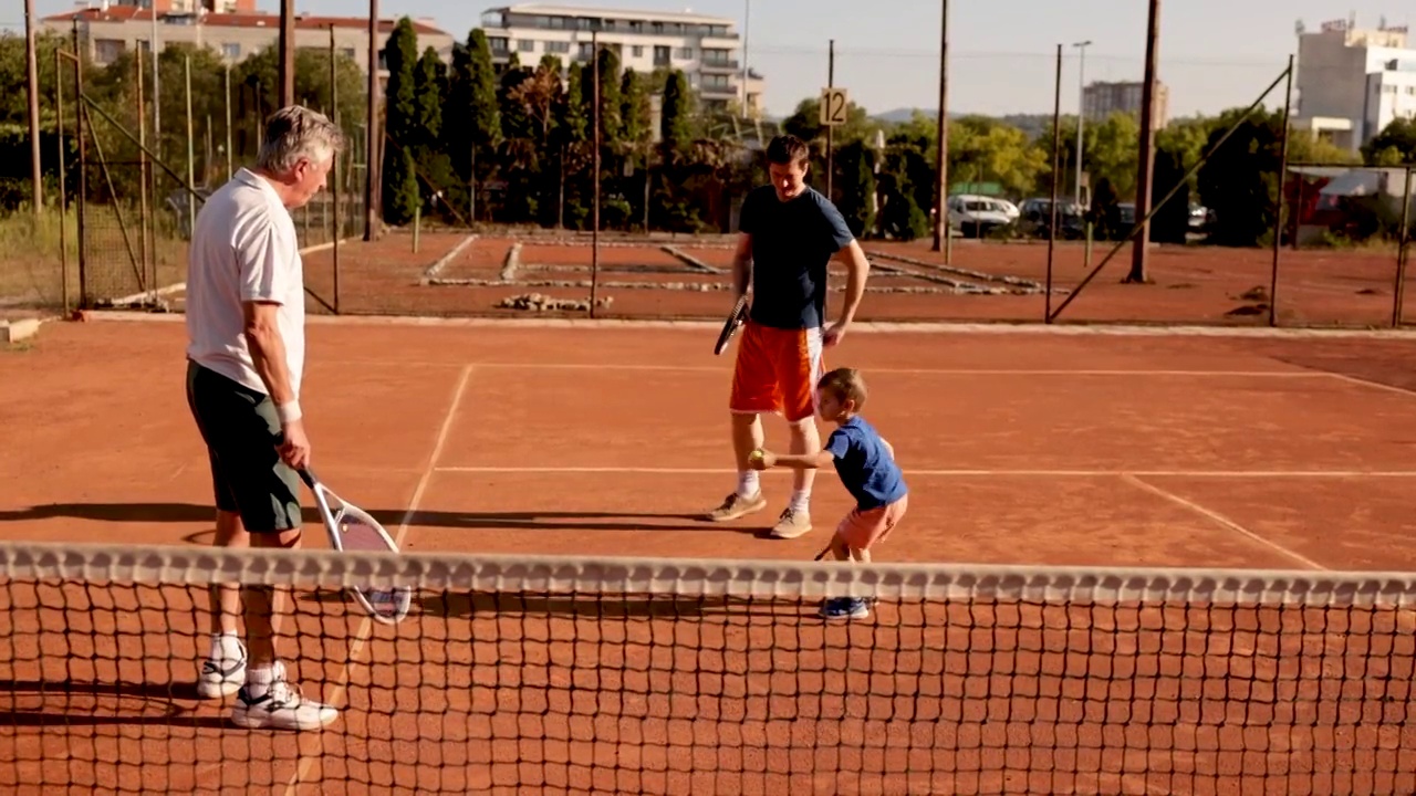 在网球场上，爷爷和爸爸正在教一个男孩打网球视频下载