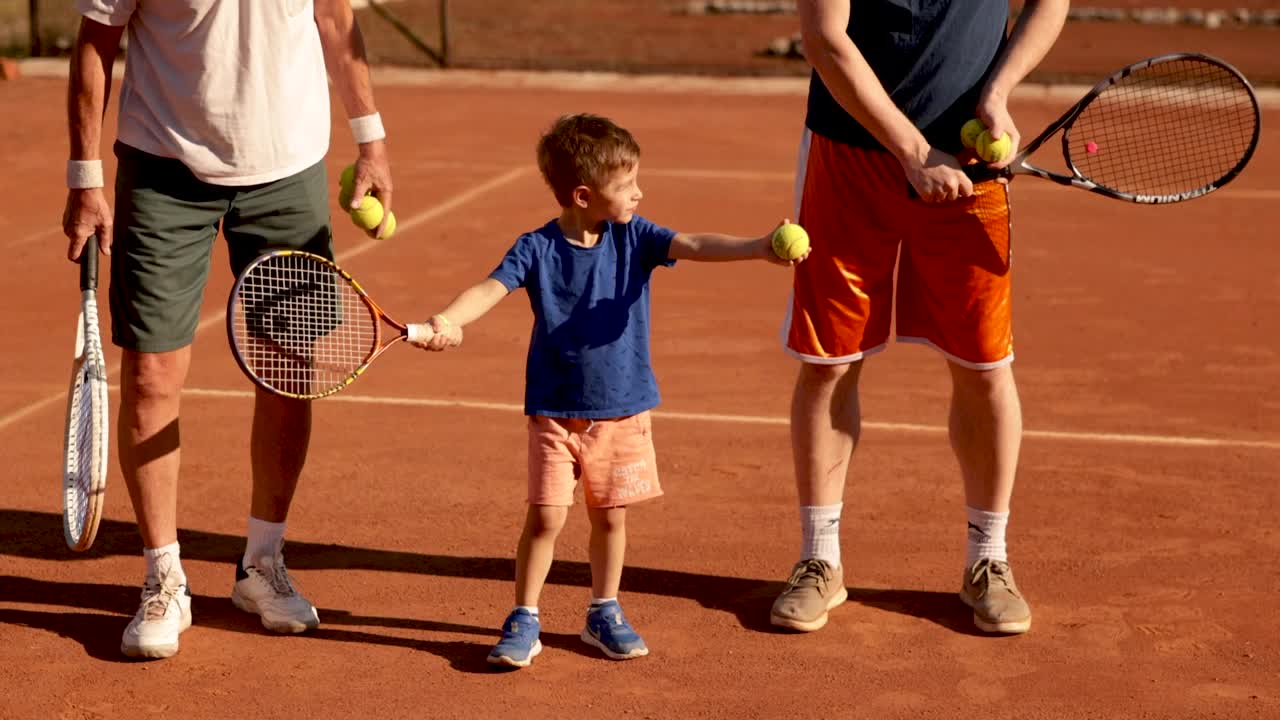 一个顽皮的小男孩，和他的家人在网球练习中玩得很开心视频下载