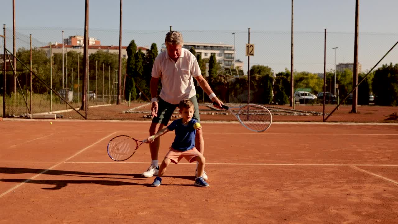 愉快和顽皮的男孩，享受与祖父的时间，在网球练习视频下载