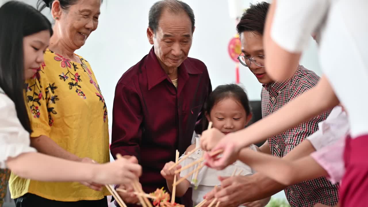 一个亚洲家庭在团圆饭上用传统食物“生鱼”庆祝中国新年视频素材