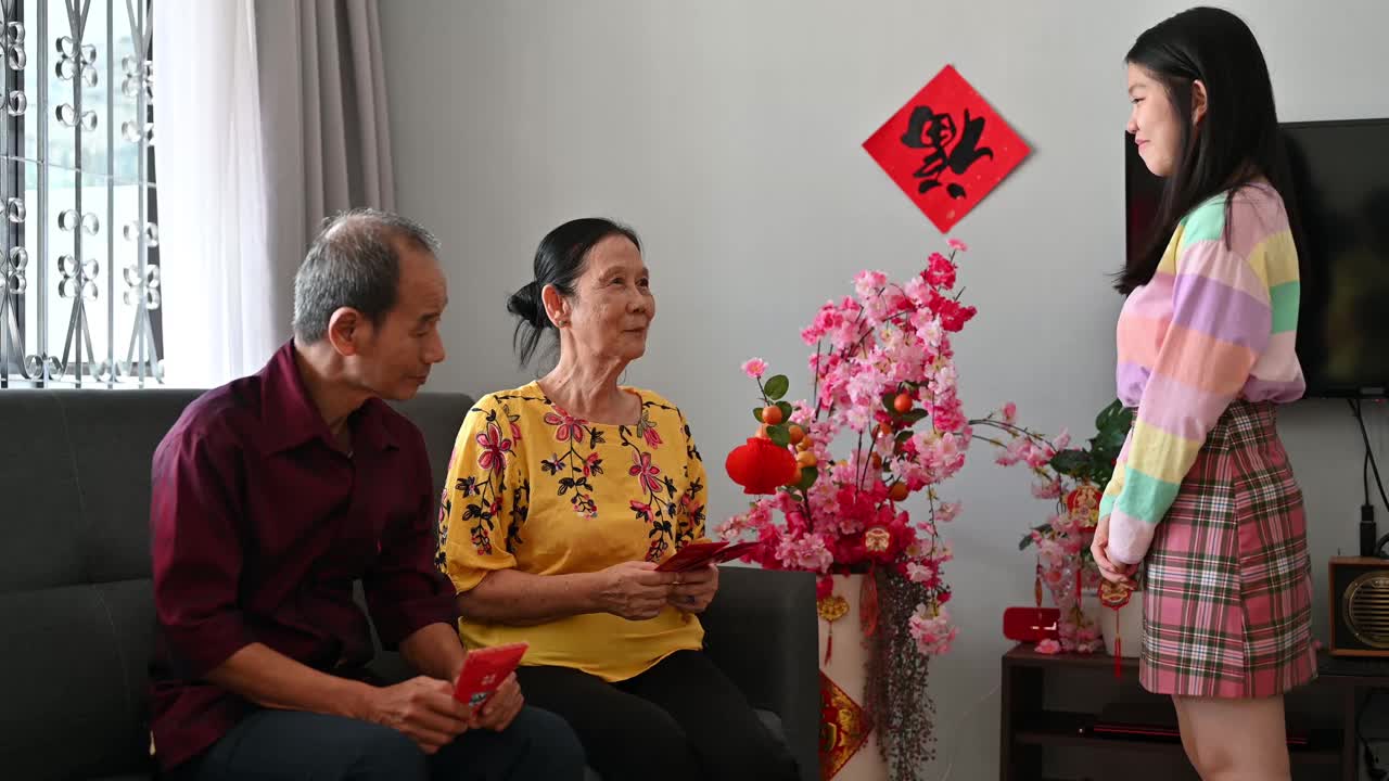 亚洲的孙子和孙女在中国新年期间在客厅问候和接受来自祖父母的春节红包(Angpow)视频素材