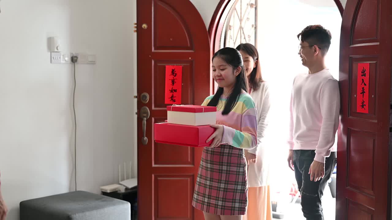 年轻漂亮的亚洲少女和父母在中国新年期间拜访她的亲戚家，赠送礼物和食物视频素材