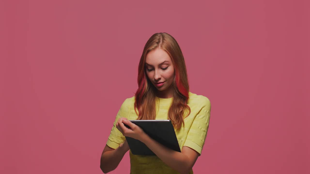 沉思的创意年轻女性与平板电脑，思考，计划做清单，梦想，创造想法在粉红色的工作室背景视频素材