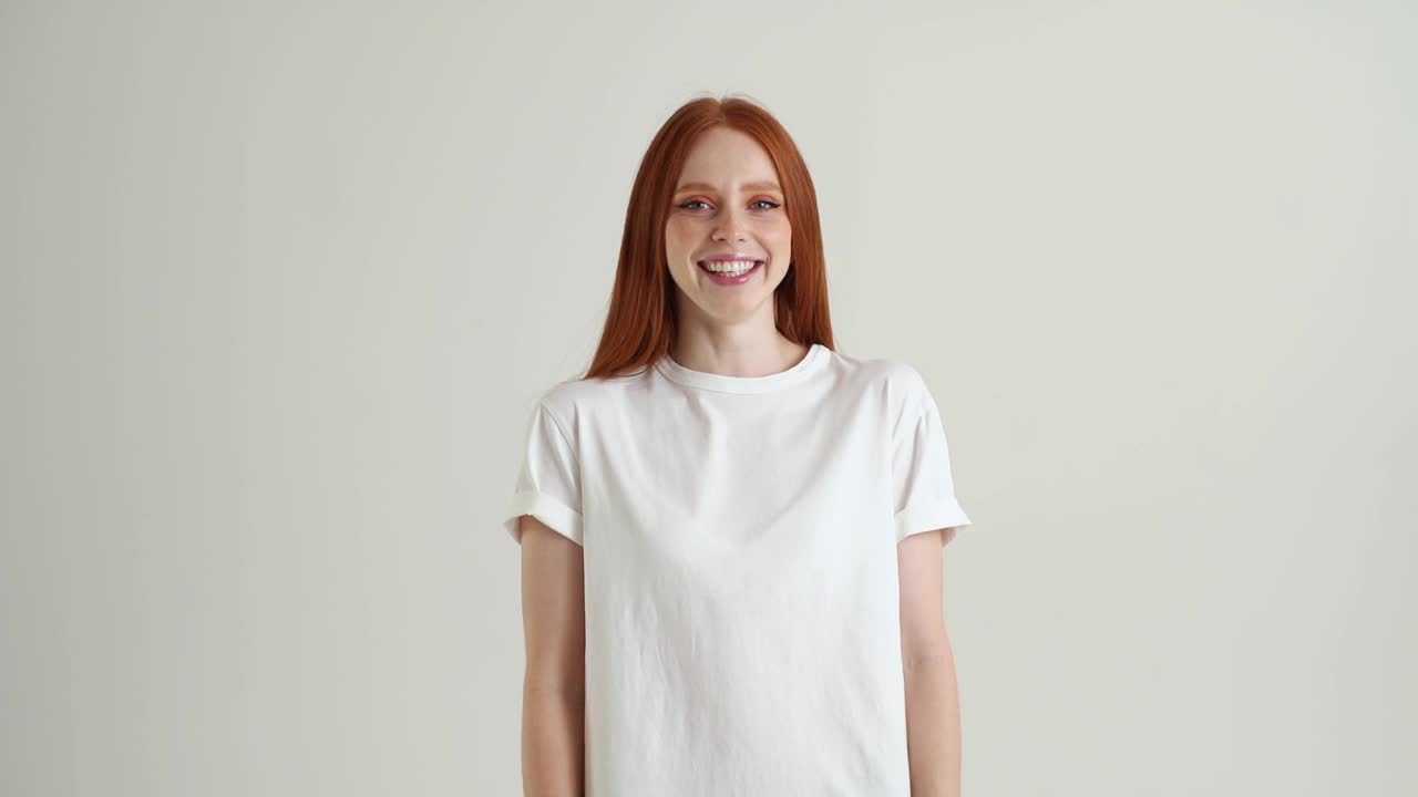 大笑迷人的年轻女子肖像有乐趣和看着相机，站在白色孤立的背景在工作室视频素材