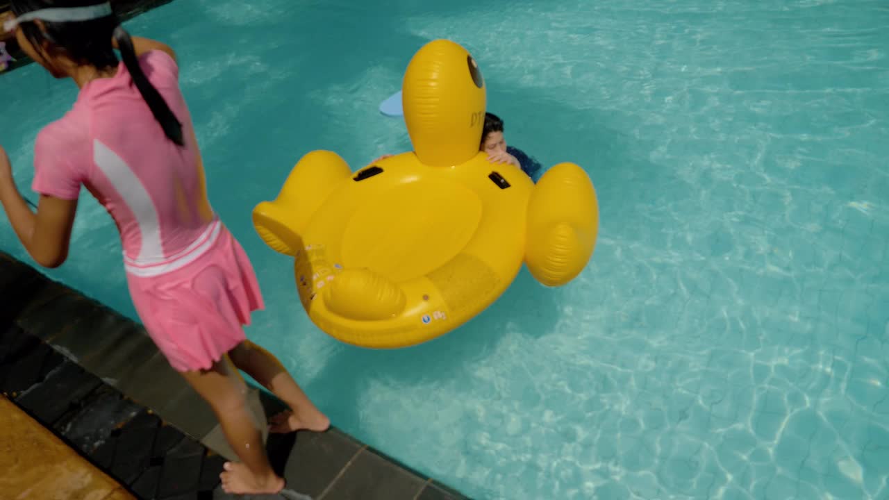 快乐的亚洲落在黄色鸭橡胶漂浮在游泳池假期与家人，生活理念。视频素材
