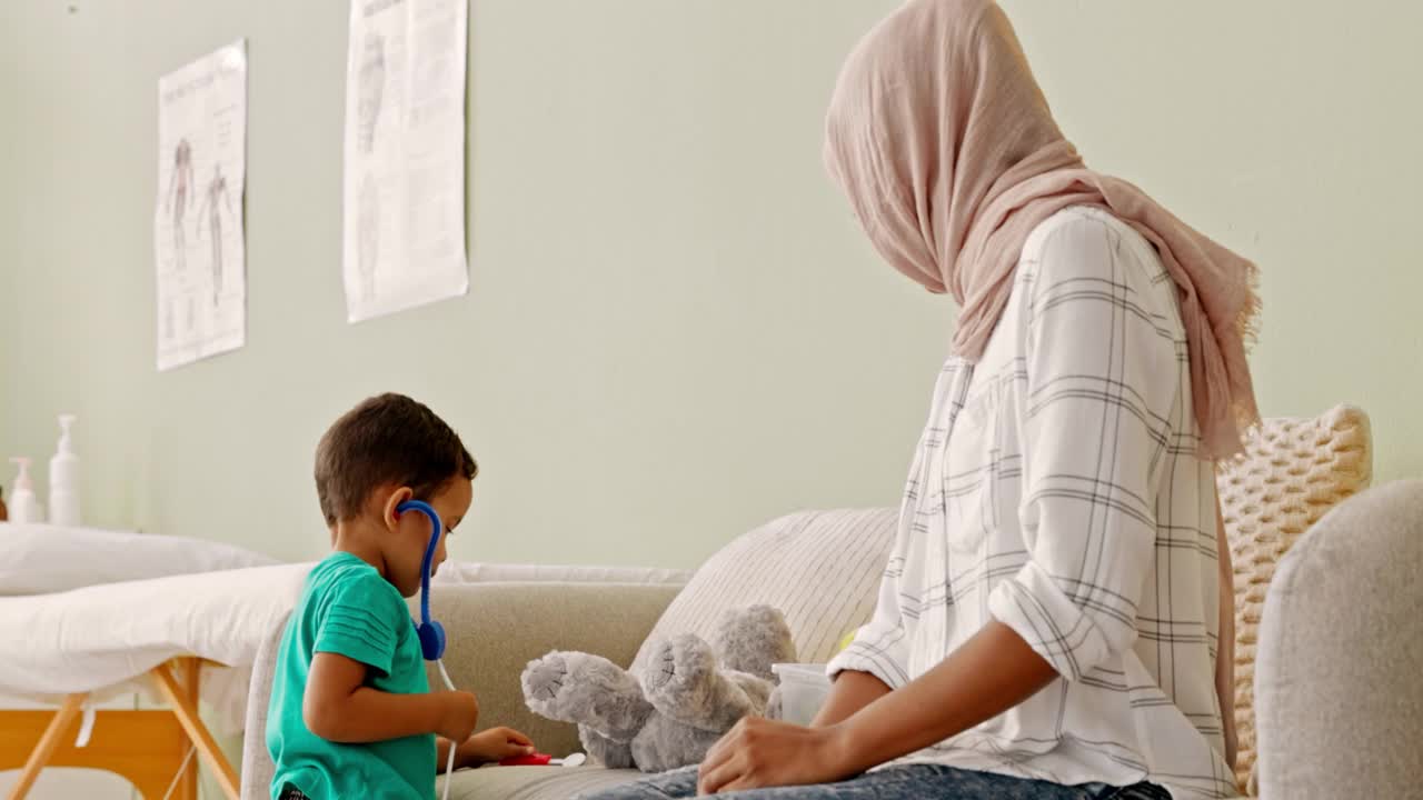 一个小男孩用听诊器在一家现代化医院和他的母亲玩耍的4k视频片段视频素材