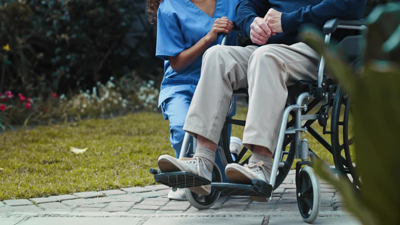 一个女护士坐在外面和一个坐轮椅的老年病人坐在一起的4k视频视频素材