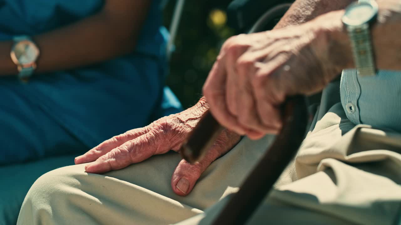 4k视频中一名女护士坐在外面揉她的老年病人的手视频素材