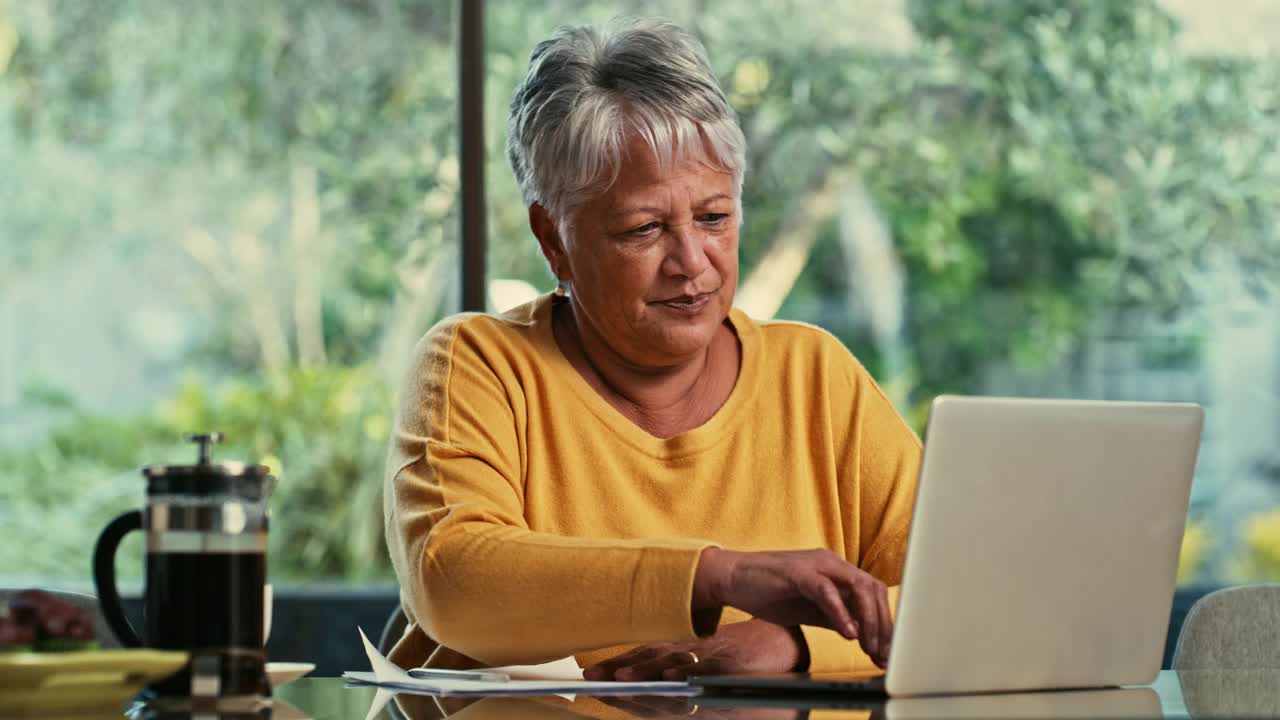 一名高级女性在家里用笔记本电脑处理文书工作的4k视频视频下载