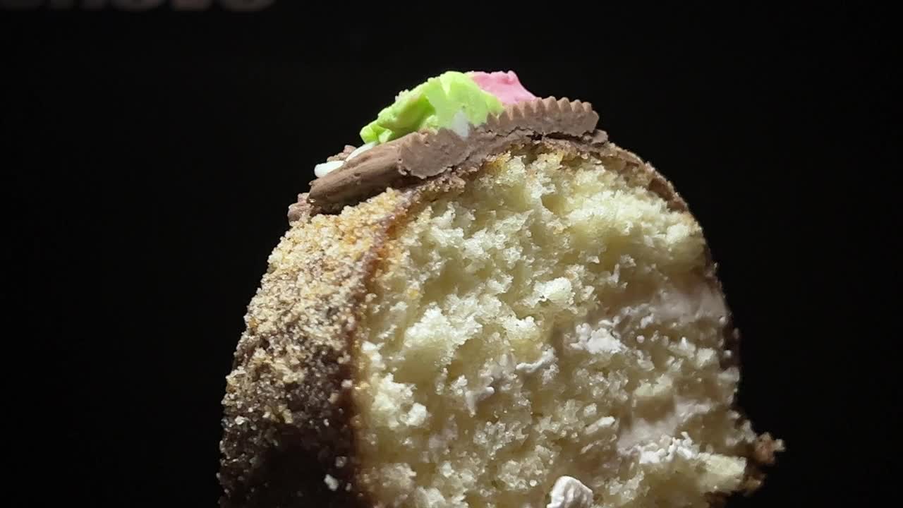 一块带有奶油的海绵蛋糕在黑色背景上旋转。视频下载