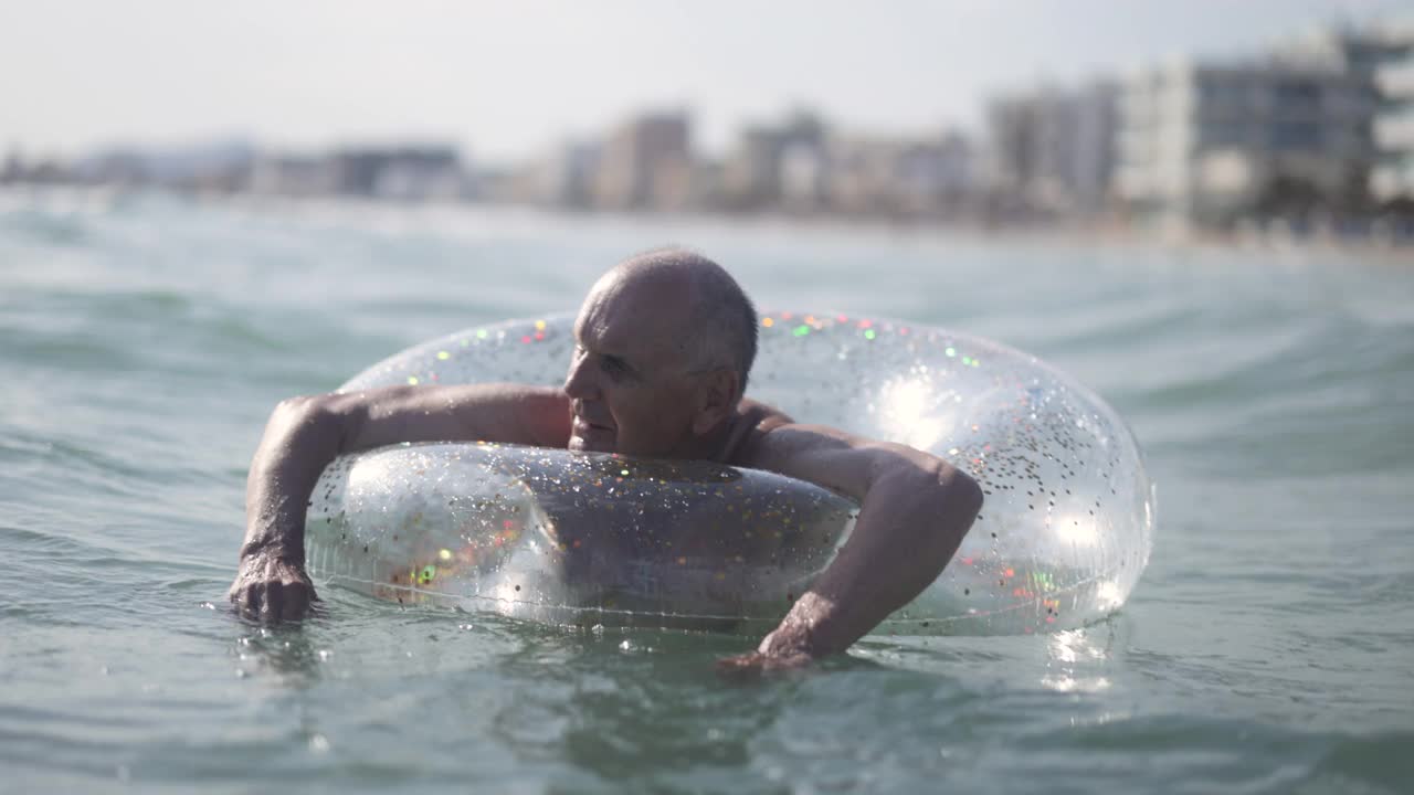 快乐的老人享受漂浮在海上的戒指视频素材