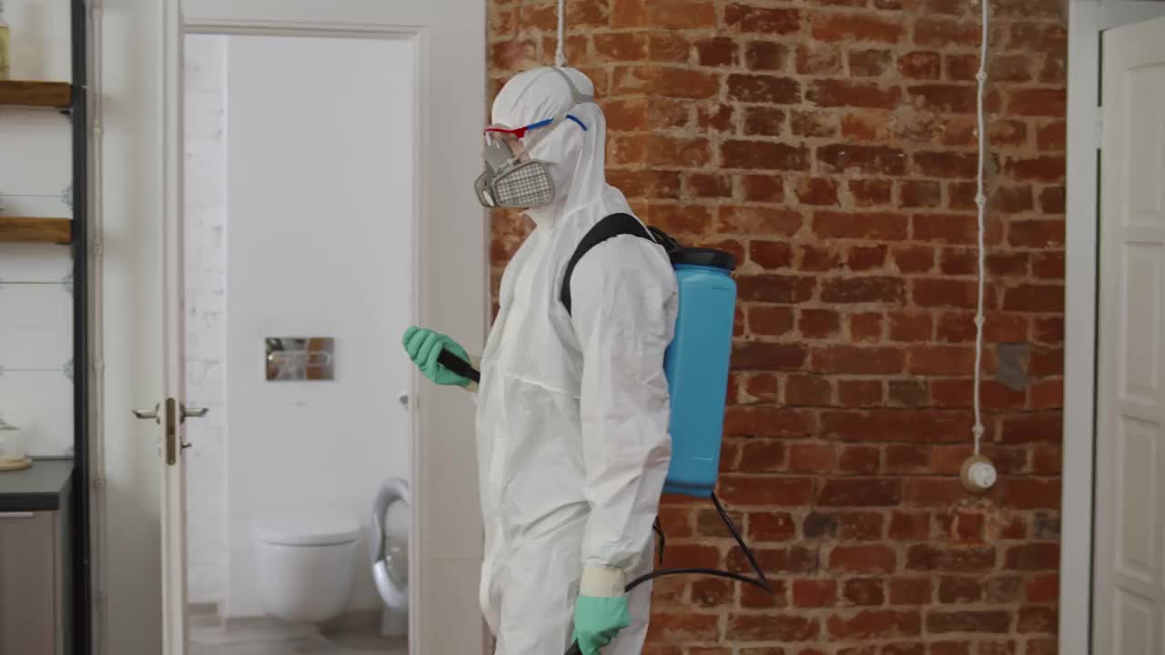 一名男子穿着个人防护装备在公寓内进行消毒。实时视频素材