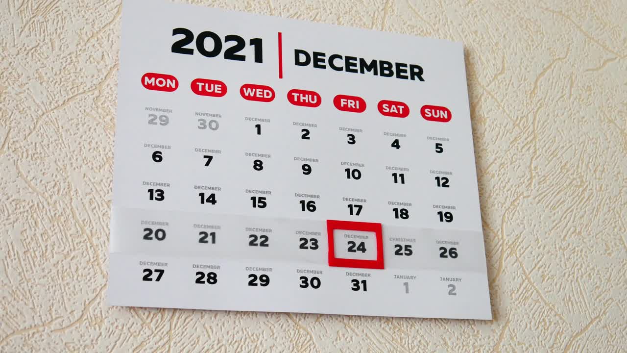 墙上挂历2021年12月的漂亮一页特写，一只男性的手将红色光标移动到圣诞节日期视频素材