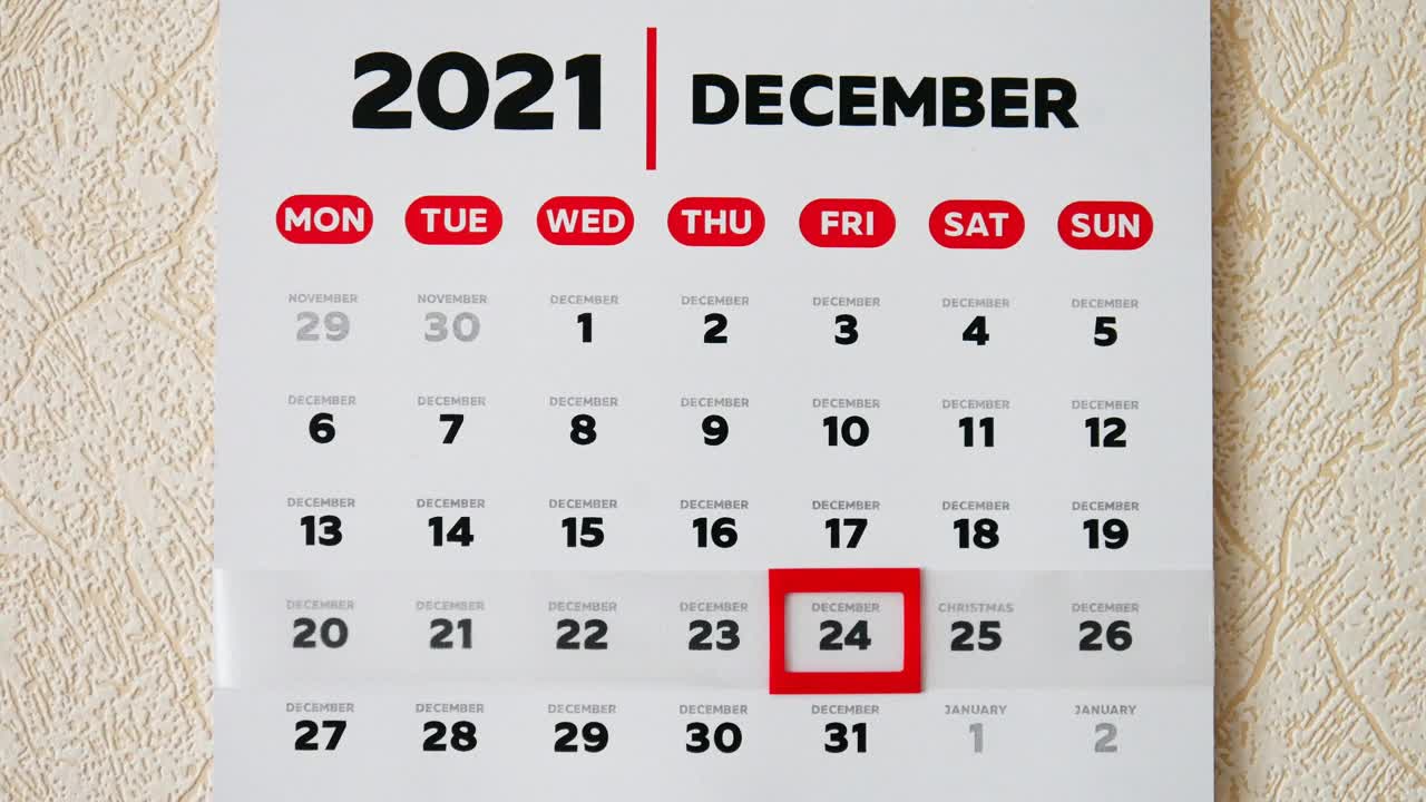 墙上漂亮的2021年12月日历，一根男性手指将红色光标移动到圣诞节日期特写视频素材