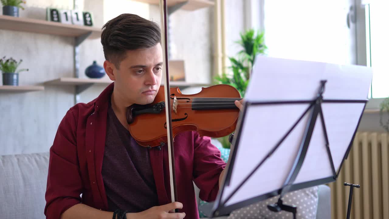 年轻的小提琴家在家里练习演奏视频下载