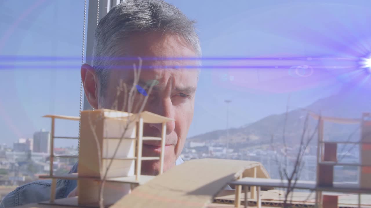 动画的蓝色光束和镜头耀斑男性建筑师看着建筑模型视频素材