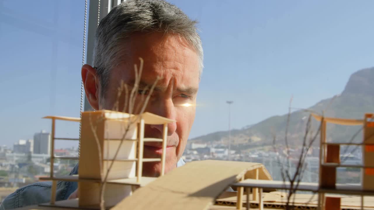 动画光束和镜头耀斑在男性建筑师看着建筑模型视频下载
