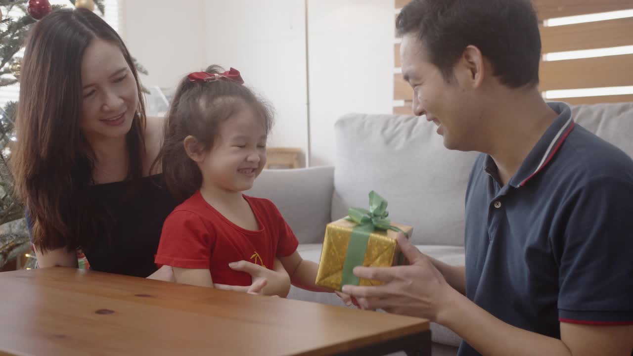 年轻的亚洲父亲给礼物盒给他的小女儿惊喜。视频素材