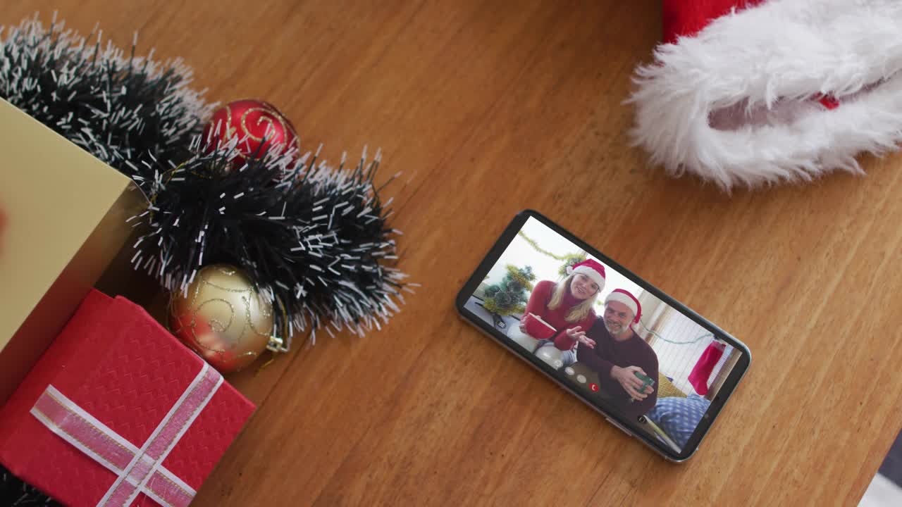 戴着圣诞帽微笑的白人夫妇在智能手机上进行圣诞视频通话视频下载