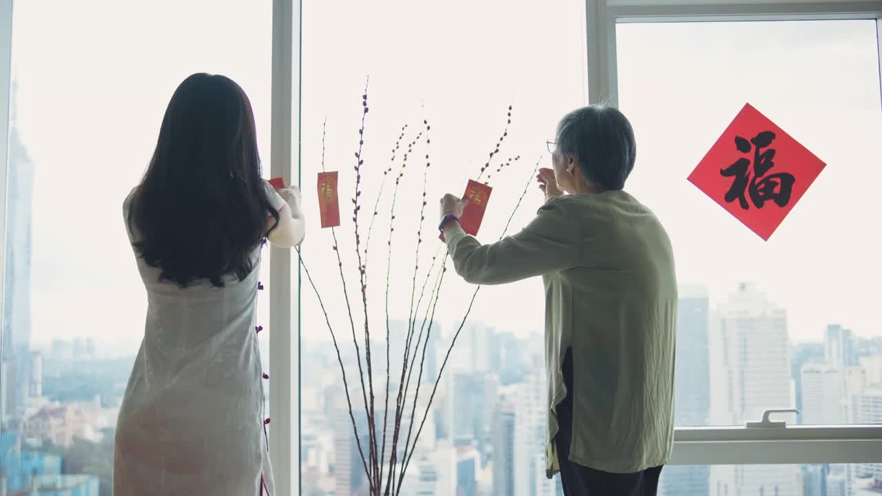 中国新年老女人和她的女儿装饰房子客厅用柳树和红包昂炮装饰准备家庭团聚视频素材