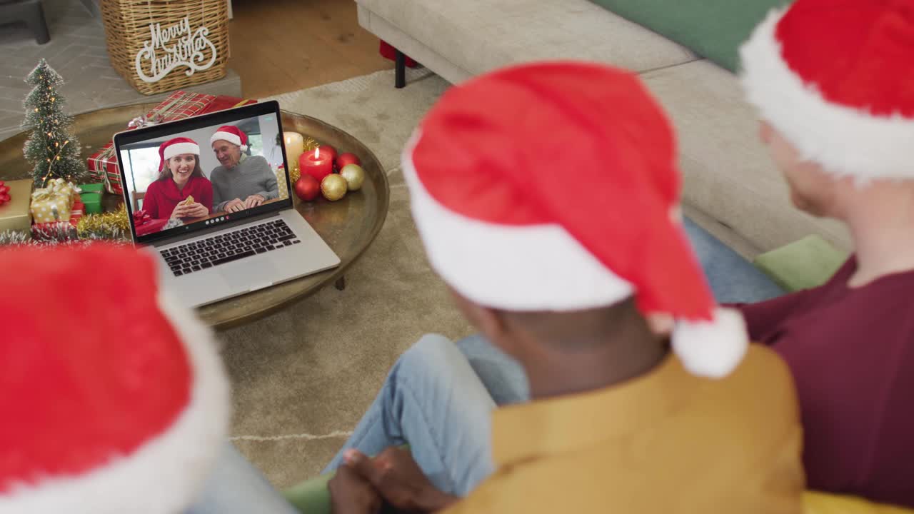 不同的家庭戴着圣诞帽，用笔记本电脑进行圣诞视频通话，屏幕上是幸福的家庭视频下载