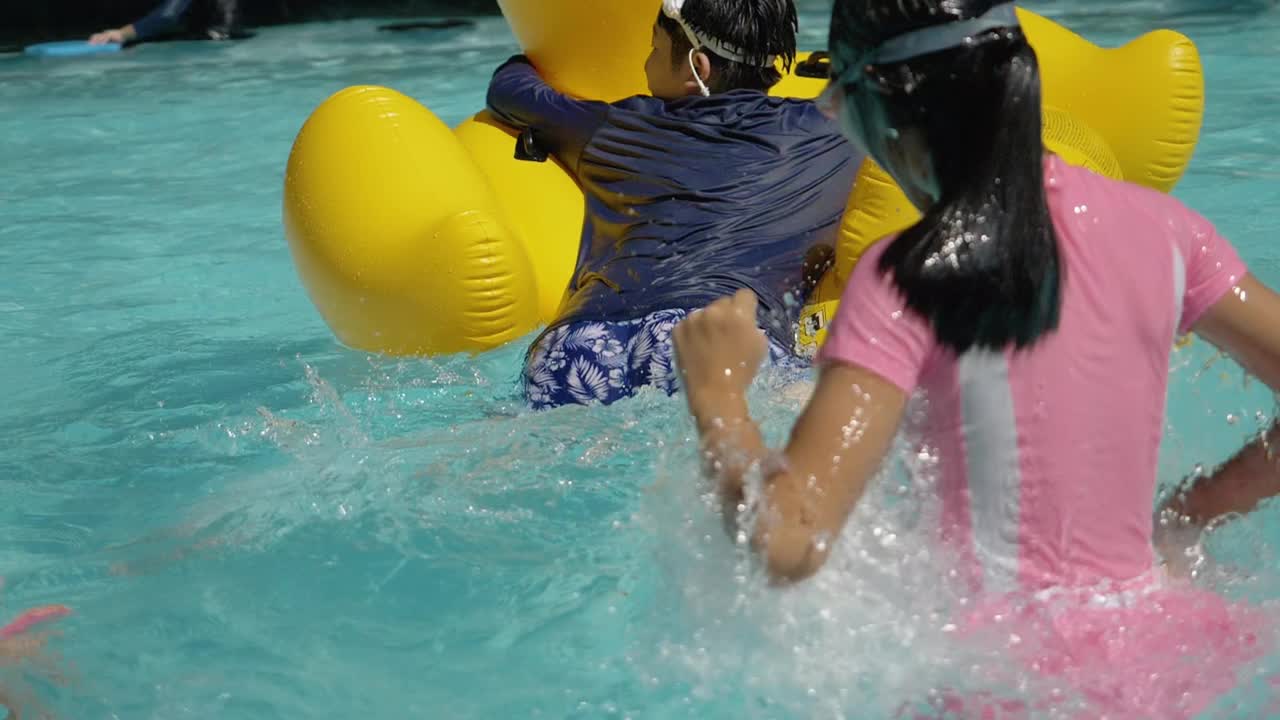 快乐的亚洲儿童在度假期间与家人在酒店或度假胜地一起在泳池中玩黄鸭橡皮艇，生活理念。视频素材