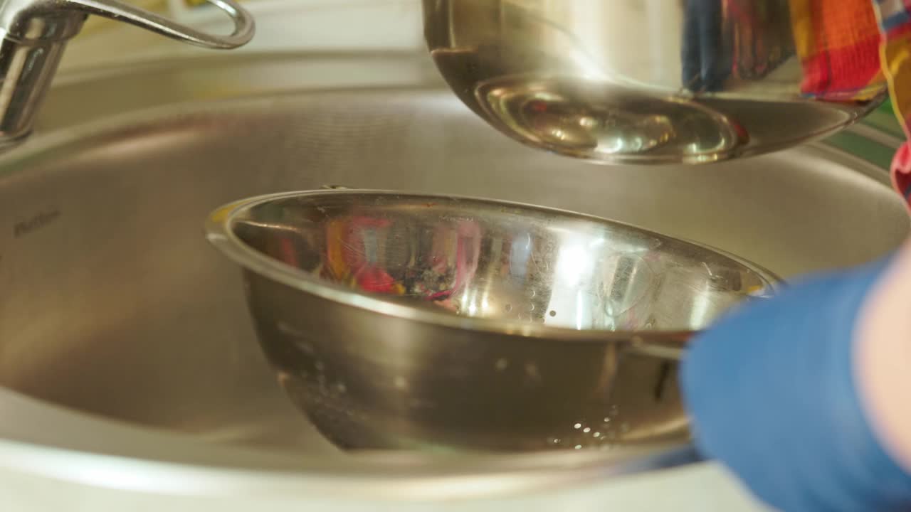 戴上蓝色手套，用厨房水槽上的漏勺把意大利面沥干视频素材