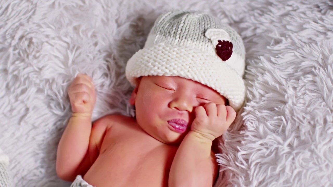 快乐的新生儿穿着可爱的服装躺在灰色地毯的背景上睡觉，舒适和安全。可爱的亚洲婴儿在婴儿床上睡觉和打盹视频素材