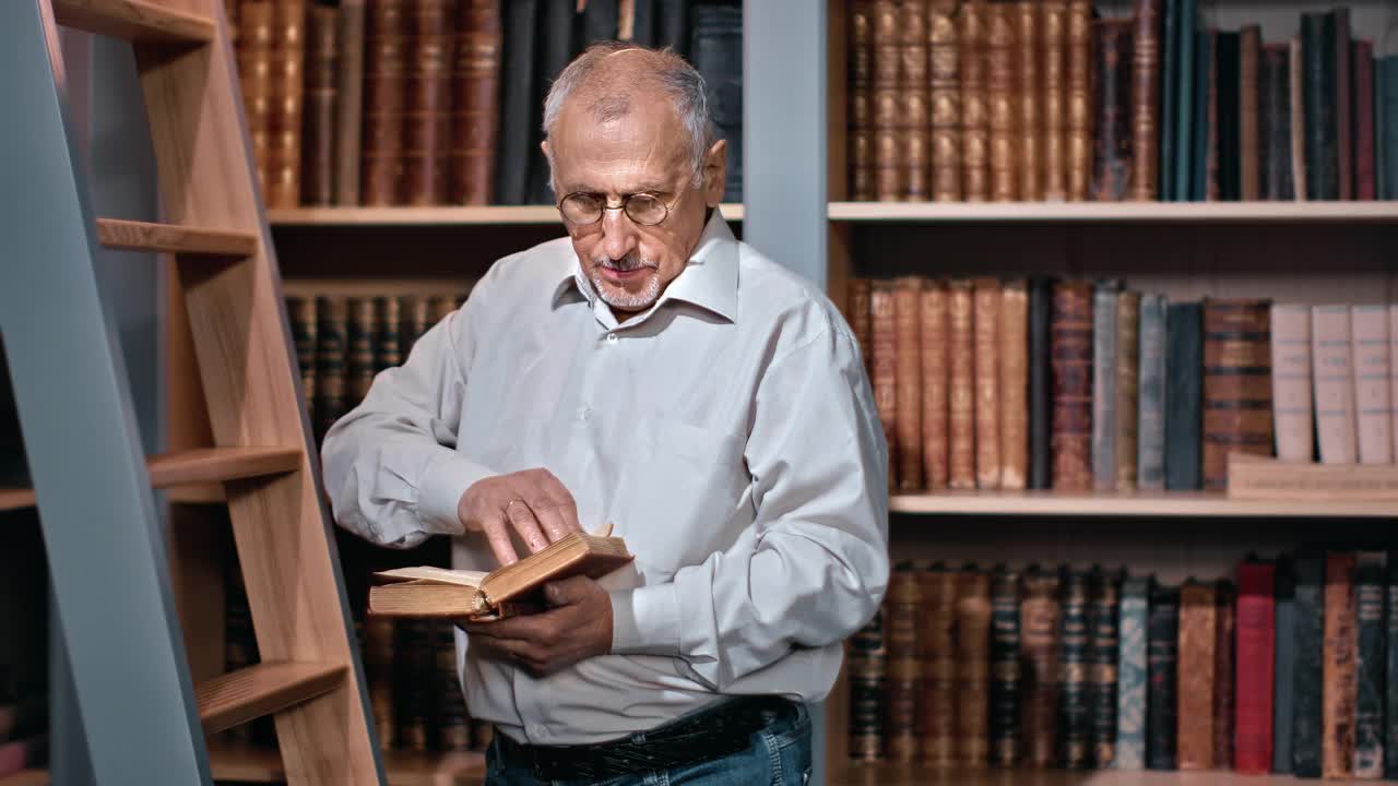 70多岁的爷爷在公共图书馆的木楼梯上读着古色古香的书视频素材