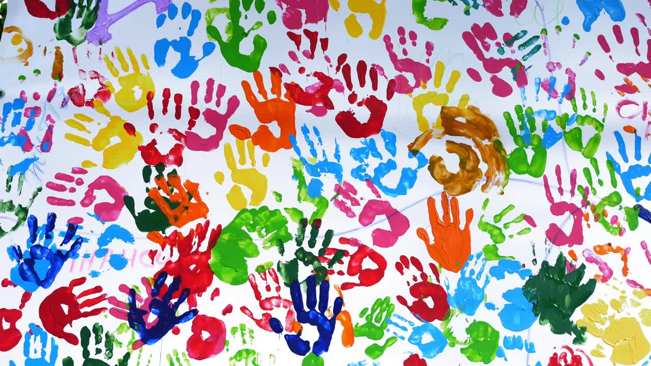 人类的手掌。彩色的手印。特写镜头。艺术。许多彩色的人类手掌印在白色的背景上，白色的墙壁或画布上视频素材