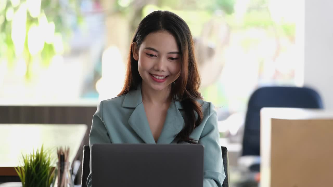 一位女员工用电脑展示了一张对公司的销售目标满意的笑脸。视频下载