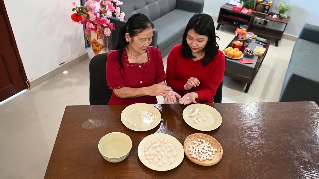 一位亚洲的奶奶和她的孙女正在为庆祝中国新年而准备汤圆视频购买