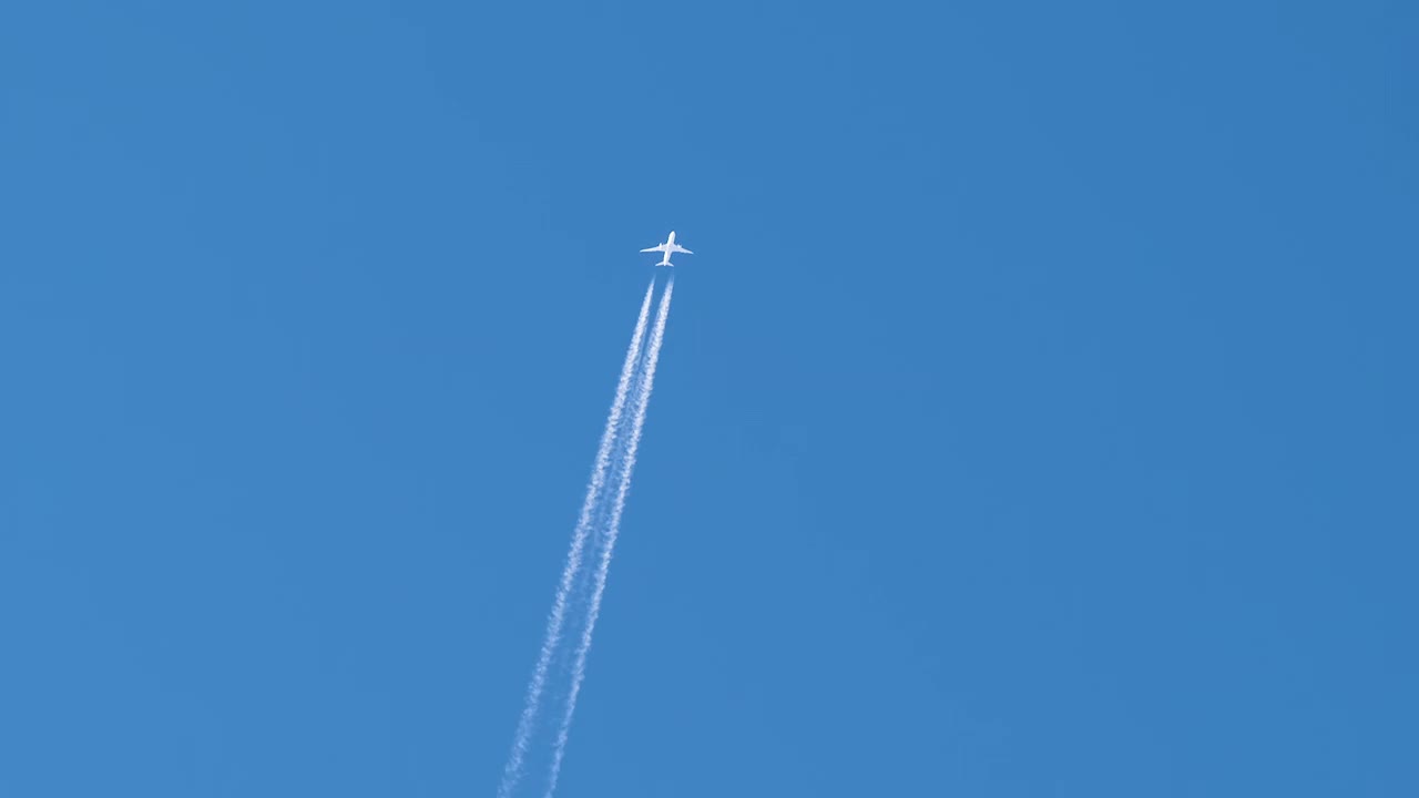 远处的喷气式客机在晴空万里的高空飞行，留下白色的烟雾和尾迹。航空运输的概念视频素材