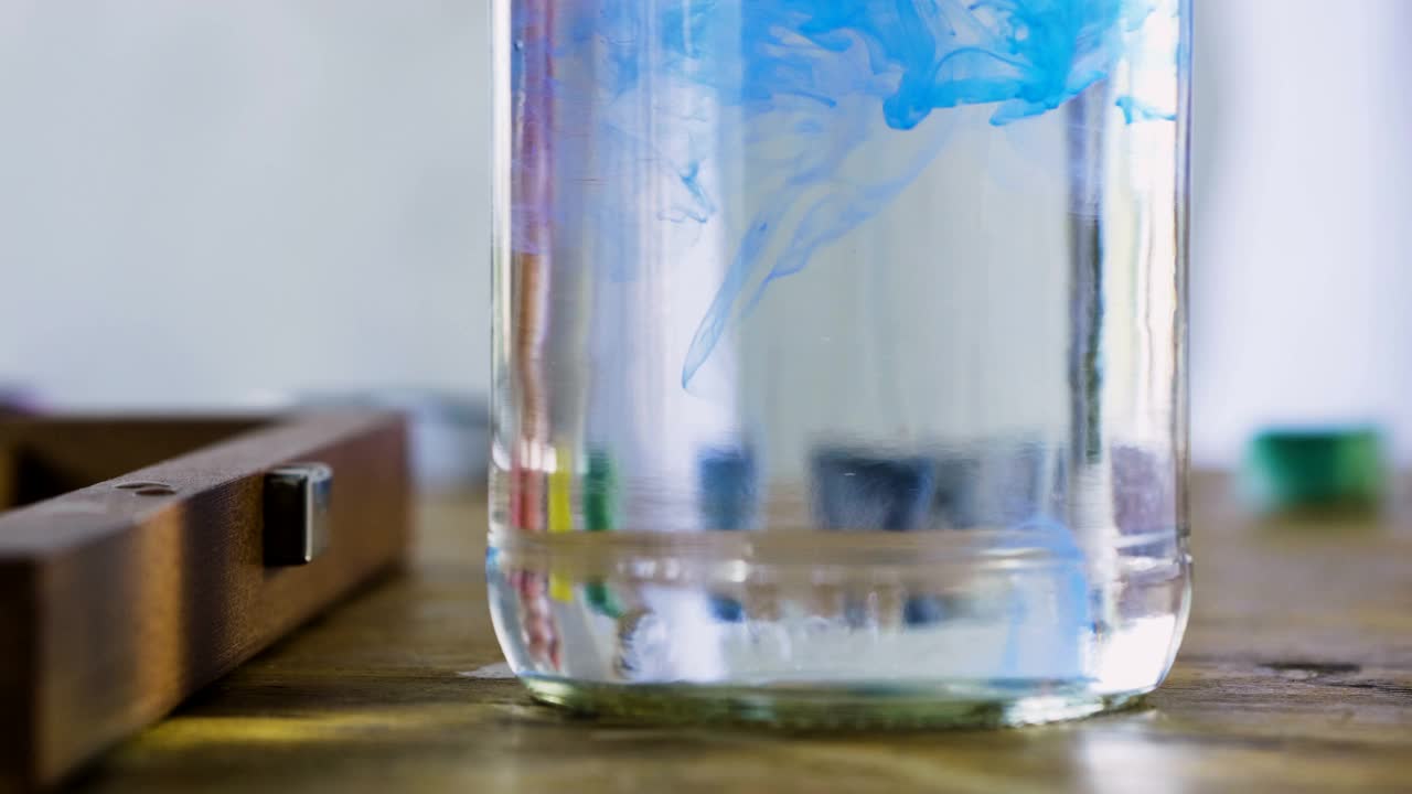 水彩画。蓝色溶解在一杯水中。4 k视频下载